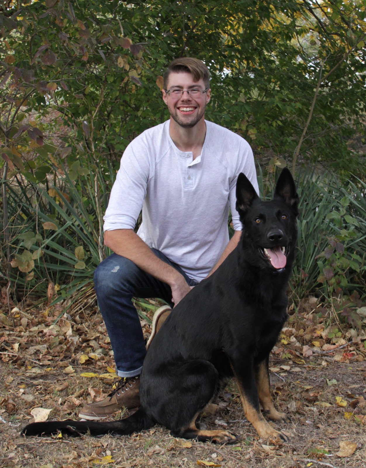 A photo of dog trainer Chase Lee kneeling next to his German Shepard named Bravo.